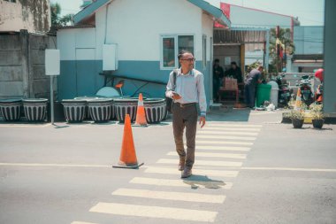 Bir adam büyük bir binanın önündeki yaya geçidinde tesadüfen yürüyor, güzel bir günde temiz havanın tadını çıkarıyor.