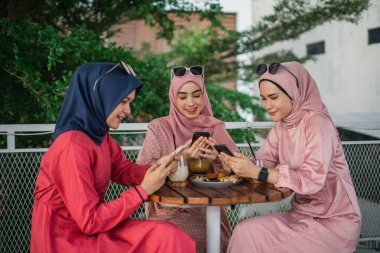 Arkadaşlar bir kafede telefonlarıyla eğlenirken lezzetli yemeklerle kaynaşıyorlar.