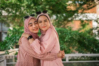 Resimli bir parkta kucaklaşan iki neşeli kız kardeş güçlü dostluk bağlarını gösteriyorlar.