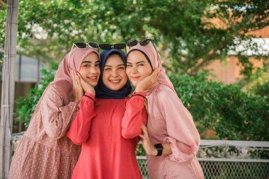 Üç neşeli kadın birlikte poz veriyor, arkadaşlıklarını ve mutluluklarını sergiliyorlar..