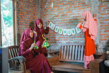 Üç neşeli kız, geleneksel kıyafetleriyle, etrafı dekorla çevrili bir şekilde neşeyle kutluyor.