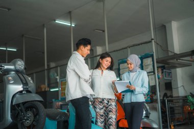 Bir galeride motosiklet isteyen Müslüman bir satıcı bir çifte açıklama yapıyor.