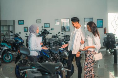 Bir galeride yeni bir motosiklete bakan Müslüman bir satıcı.