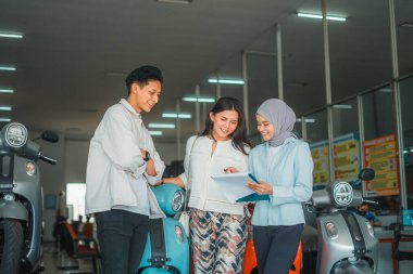 Peçeli satıcı bir kadına ve erkek arkadaşına galeride motosikletli tipleri sorarken