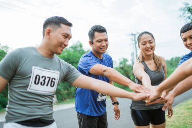 Asyalı sporcu ellerini bir araya getirerek iyi takım çalışmasını gösteriyor.