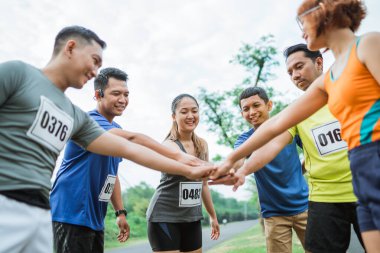Asyalı koşucular ellerini birleştirerek iyi bir takım çalışması sergiliyorlar.