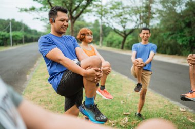 Asain erkek koşucu maratondan önce diğer insanlarla esniyor.