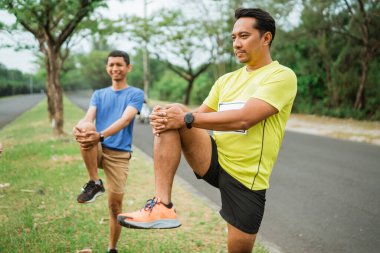 Asyalı koşucu maratondan önce ısınıyor ya da esniyor
