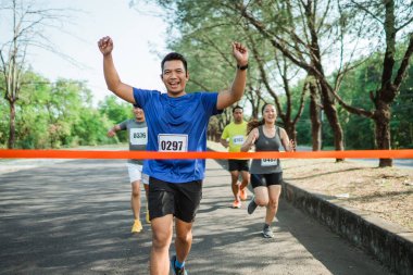 Maratonda bitiş çizgisine doğru koşan Asyalı erkek sporcu