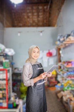 Canlı bir market ortamında, genç bir kadın görevleri için bir tablet kullanıyor.