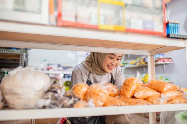 Neşeli bir esnaf, marketinde çeşitli ürünleri dikkatlice düzenliyor.