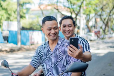 İki arkadaş anı yakalamak için selfie çekerken heyecan verici bir scooter yolculuğunun tadını çıkarıyor.
