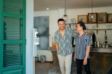 İki yakın arkadaş gülüyor ve birbirleriyle eğleniyorlar. Şık, modern bir kafe içinde.