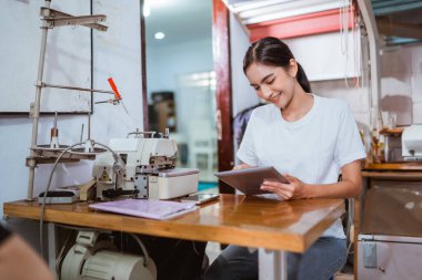 Güzel Asyalı prodüksiyon ekibi vitrinlerde dijital tablet üzerinde çalışıyor.