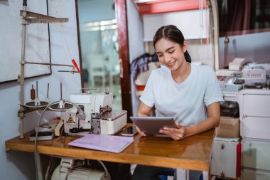 Güzel Asyalı çalışan, vitrin tedavisinde dijital tableti üzerinde çalışıyor.