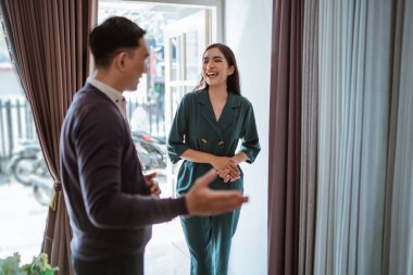 Asyalı erkek esnaf tarafından karşılanan Asyalı güzel müşteri, iç mekan dükkanına girerken gülüyor.