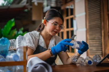 Plastik şişe yapmak için elinde kesici tutan Asyalı bir kadın.