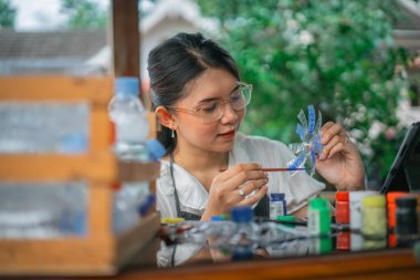 Geri dönüştürülmüş plastik şişe sanatını resmeden yaratıcı Asyalı kadın.