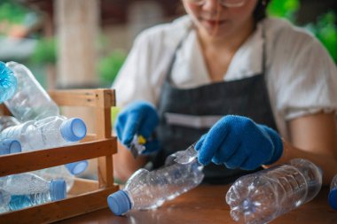 Sürdürülebilir yaşam tarzı plastik şişe atıklarından el yapımı zanaat yapan bir kadın.