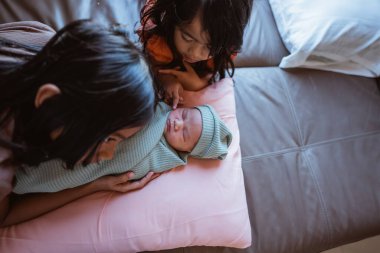 Kardeşler, sevimli bebekleriyle sıcak bir kanepede eğlenerek anılarını yaratıyorlar.