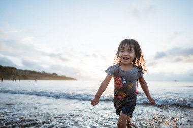 Neşeli bir çocuk, güzel bir gün batımında okyanus dalgalarında enerjik bir şekilde süzülür.