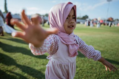 Geleneksel kıyafetler giymiş neşeli, mutlu bir çocuk parkta güneşli bir günün tadını çıkarıyor.