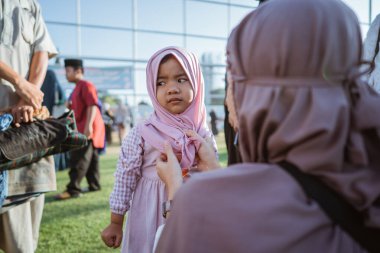 Pembe elbiseli genç bir kız canlı bir açık hava ortamında bir yetişkinle etkileşime giriyor..