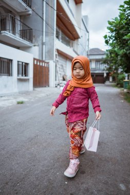 Renkli kıyafetli neşeli bir kız huzurlu bir caddede mutlu bir şekilde geziniyor, gününün tadını çıkarıyor.