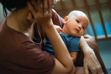 Huzurlu bir an, sevgi dolu bir annenin bebeğini nazikçe kucağına alıp sevgiyi ve ilgiyi somutlaştırdığını gösterir.