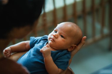 Sevgi dolu bir anne, kıymetli bebeğini nazikçe sıcak, samimi ve sevgi dolu bir ortamda kucaklar.