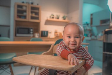 Neşeli ve mutlu bir bebek. Parlak, modern bir mutfak ortamında eğleniyor.