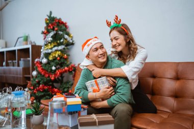 Ağacın yanındaki şenlikli Noel sezonunda neşeli bir çift birlikte vakit geçiriyorlar.