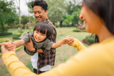 Güzel bir kadın, bir çocuğun iki elini de açık havada uçan bir adam gibi taşırken tutar.