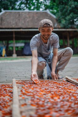 Bir adam kuru bir rafta renkli meyveler hazırlar, güneşli bir yaz gününün tadını çıkarır.