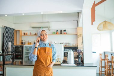 Peçeli kadın kafe sahibi kahvecideyken cep telefonu görüşmesi yapıyor.