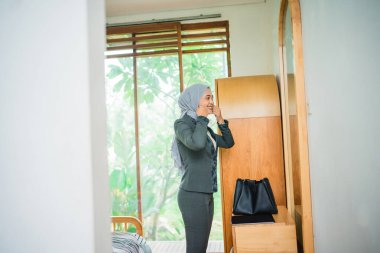 Peçeli kadın ofis çalışanı odasında giyinmeye hazırlanıyor.