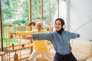 İki kadın evde yoga yapıyor, arkadaşlıklarını ve genel sağlıklarını geliştiriyor.