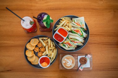 Manzaralı nugget, sosis ve patates kızartması ve ahşap bir masada biraz içki.