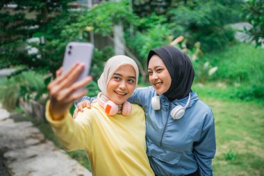 İki neşeli arkadaş açık hava ortamında neşeli bir selfie çekiyor.