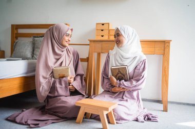İki güzel Asyalı Müslüman kadın kutsal bir Müslüman kitabı tutuyor.