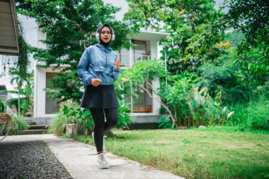 Asyalı kadın sabah parkta koşarken kulaklık takıyor.