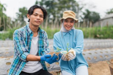 İki birey, fidelerle etkileyici bahçıvanlık çabalarını gururla sergiliyor.