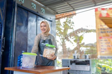 Neşeli bir satıcı, lezzetli atıştırmalıklar ve ferahlatıcı içeceklerle dolu enerjik yiyecek tezgahını yönetiyor.