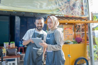 İki hevesli barmen yeni teknolojilerini kullanarak canlı bir yemek standında birlikte çalışmaktan mutlu oluyorlar.