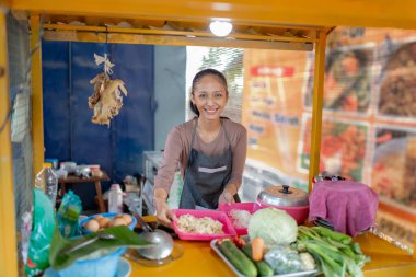 Neşeli bir satıcı, yerel bir lokantada taze malzemeler hazırlıyor.