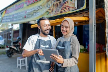 İki barmen dükkanlarının önünde tablet kullanırken günlük iş deneyimlerini tartışıyor.