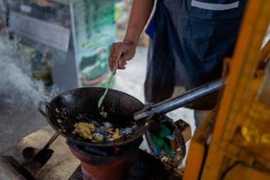 Yetenekli bir sokak şefi tavada taze malzemeler pişiriyor, aşçılık yeteneğini gösteriyor.