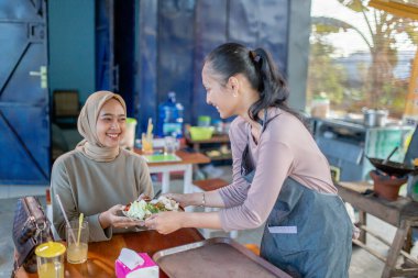 İki kadın, kafede lezzetli yemeklerle keyifli vakit geçiriyorlar.