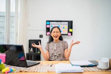 Şık ve hareketli çalışma ortamında heyecanını ifade eden neşeli bir kadın.