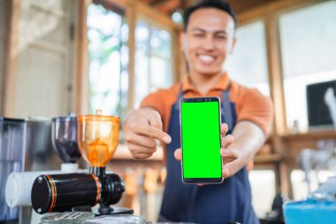 Erkek baristanın elinde bulanık arkaplanı olan boş bir ekran telefonu var.